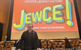 Kaplan pose sous le logo JewCE à JewCE : The Jewish Comics Experience au Center for Jewish History à Manhattan, le 10 novembre 2024. (Crédit : Jay Deitcher)