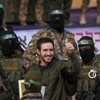 L'otage civil israélien Omer Shem Tov (au centre) vêtu d'un uniforme ressemblant à celui des soldats de l’armée israélienne, est entouré de terroristes armés du Hamas avant d'être remis à la Croix-Rouge lors d'une cérémonie de propagande à Nuseirat, dans le centre de la bande de Gaza, le 22 février 2025. (Crédit : Abdel Kareem Hana/AP)