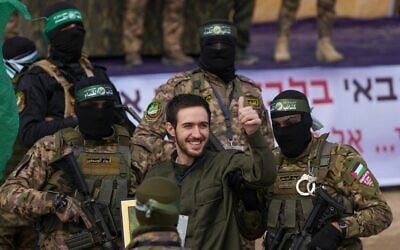 L'otage civil israélien Omer Shem Tov (au centre) vêtu d'un uniforme ressemblant à celui des soldats de l’armée israélienne, est entouré de terroristes armés du Hamas avant d'être remis à la Croix-Rouge lors d'une cérémonie de propagande à Nuseirat, dans le centre de la bande de Gaza, le 22 février 2025. (Crédit : Abdel Kareem Hana/AP)