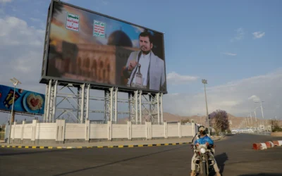 Des Yéménites passent sous un panneau d'affichage affichant une photo d'Abdul Malik al-Houthi, le chef du groupe rebelle Houthi. Le texte en arabe dit « mort à l'Amérique, mort à Israël », à Sanaa, Yémen, mardi 18 mars 2025. (Crédit : Osamah Abdulrahman/AP)