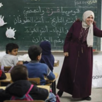 Une enseignante de l'école élémentaire Al-Nasr, dans la ville de Gaza, à côté d'un tableau noir sur lequel on peut lire « Vous êtes le Toufan » (le déluge), une allusion au Déluge d'al-Aqsa, le nom donné par le Hamas au pogrom du 7 octobre 2023 perpétré dans le sud d’Israël, le 23 février 2025. (Crédit : Omar AL-QATTAA / AFP)