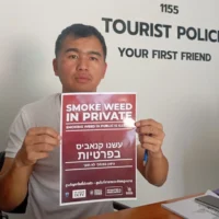 D'Tomarito, un agent de la police touristique, tient un panneau avec des instructions en hébreu sur la façon de se comporter pour les touristes israéliens à Pai, en Thaïlande. (Crédit : Eliyahu Freedman)