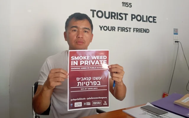 D'Tomarito, un agent de la police touristique, tient un panneau avec des instructions en hébreu sur la façon de se comporter pour les touristes israéliens à Pai, en Thaïlande. (Crédit : Eliyahu Freedman)