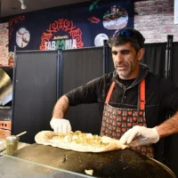 Raif Rashed, Druze israélien propriétaire de Taboonia, dépose du labneh sur une pita à New York, en mars 2025. (Crédit : Jackie Hajdenberg/ JTA)