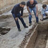 Les archéologues Zubair Adawi et Kfir Arbiv, directeurs des fouilles pour le compte de l'Autorité des antiquités d'Israël, examinent une rareté, à savoir un squelette entravé par des anneaux de fer découvert dans les vestiges d'une église à environ trois kilomètres au nord-ouest de Jérusalem. (Crédit : Yoli Schwartz/Autorité des antiquités d'Israël)