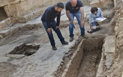 Les archéologues Zubair Adawi et Kfir Arbiv, directeurs des fouilles pour le compte de l'Autorité des antiquités d'Israël, examinent une rareté, à savoir un squelette entravé par des anneaux de fer découvert dans les vestiges d'une église à environ trois kilomètres au nord-ouest de Jérusalem. (Crédit : Yoli Schwartz/Autorité des antiquités d'Israël)