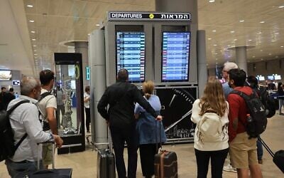 Des passagers consultent le panneau des vols à l'aéroport Ben Gurion, alors que les vols sont annulés et retardés en raison de l'assaut du Hamas, le 7 octobre 2023. (Crédit : Gil Cohen-Magen/AFP)