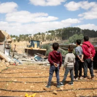Des enfants palestiniens regardent l'administration civile israélienne démolir une maison à At-Tuwani, un village de Masafer Yatta, le 7 mai 2025. (Crédit : Emily Glick)