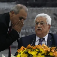 Le directeur des renseignements généraux palestiniens en Cisjordanie, Majid Faraj (à gauche), chuchote au président de l'Autorité palestinienne Mahmoud Abbas lors d'une réunion où il a demandé à rejoindre 15 agences des Nations unies, renonçant ainsi à ses promesses de s'abstenir de le faire pendant neuf mois de négociations qui devaient se terminer le 29 avril, à son siège dans la ville de Ramallah en Cisjordanie, le 1er avril 2014. (Crédit : ABBAS MOMANI / AFP)