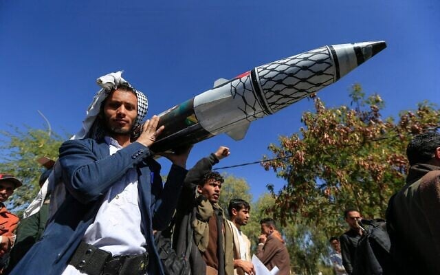 Un Yéménite portant un missile factice lors d'un rassemblement d'étudiants et de professeurs d'université dénonçant les frappes sur le Yémen et en solidarité avec les Palestiniens, dans la capitale Sanaa contrôlée par les Houthis, le 1er janvier 2025. (Crédit : Mohammed Huwais/AFP) Un Yéménite portant un missile factice lors d'un rassemblement d'étudiants et de professeurs d'université dénonçant les frappes sur le Yémen et en solidarité avec les Palestiniens, dans la capitale Sanaa contrôlée par les Houthis, le 1er janvier 2025. (Crédit : Mohammed Huwais/AFP)
