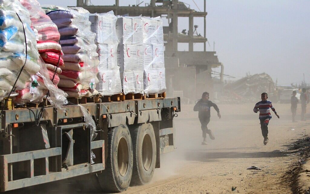 Des enfants palestiniens poursuivent un camion chargé d'aide humanitaire à Rafah, dans le sud de la bande de Gaza, après avoir franchi le point de passage de Kerem Shalom, le 18 février 2025. (Eyad BABA / AFP)
