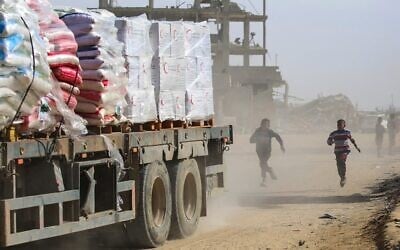 Des enfants palestiniens poursuivent un camion chargé d'aide humanitaire à Rafah, dans le sud de la bande de Gaza, après avoir franchi le point de passage de Kerem Shalom, le 18 février 2025. (Eyad BABA / AFP)
