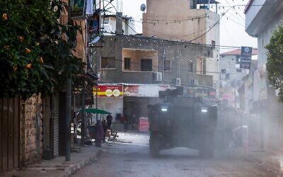 Des commerçants palestiniens regardent passer des véhicules blindés israéliens lors d'un raid dans le quartier est de Jénine, au cours d'une opération de plusieurs semaines en Cisjordanie, le 4 mars 2025. (Crédit : Jaafar ASHTIYEH / AFP)