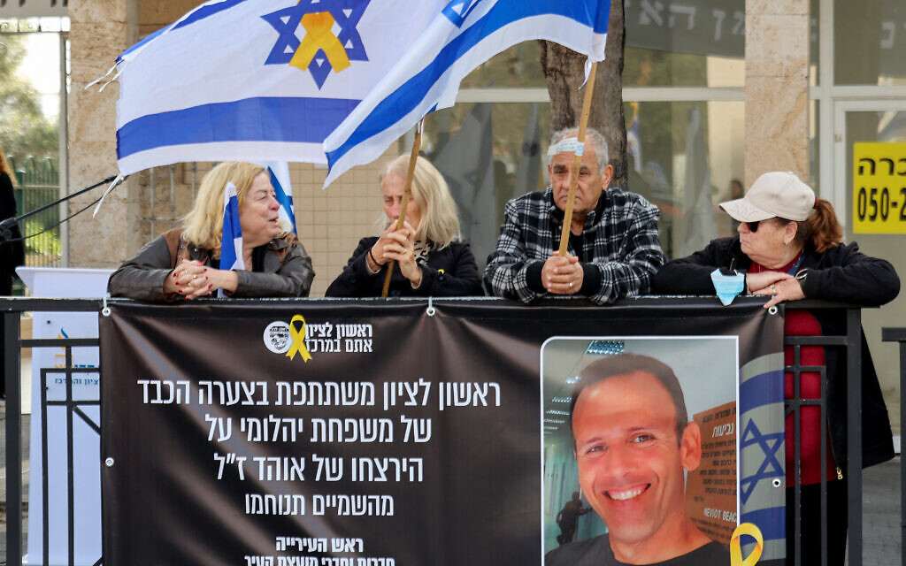 Des Israéliens tenant des drapeaux et des pancartes attendent devant la morgue de Rishon LeZion, dans le centre d'Israël, le cortège funèbre du ressortissant franco-israélien Ohad Yahalomi (photo), l'un des otages israéliens capturés par des terroristes palestiniens dans la bande de Gaza lors des attentats du 7 octobre 2023, le 5 mars 2025. (Crédit : Jack GUEZ / AFP)