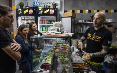 Yonatan Baleli, vendeur dans un stand de sandwichs, prépare une commande pour des clients dans la ville de Shlomi, au nord d'Israël, près de la frontière avec le Liban, le 3 mars 2025, après qu'Israël a demandé aux habitants des régions du nord de commencer à retourner dans leurs villes après un accord de cessez-le-feu du 27 novembre avec le Liban. (Crédit : KAHANA / AFP)