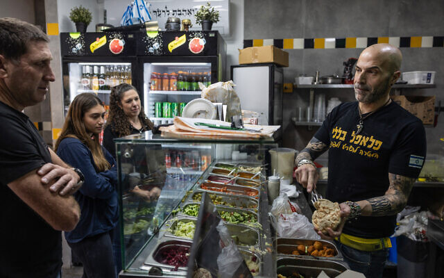 Yonatan Baleli, vendeur dans un stand de sandwichs, prépare une commande pour des clients dans la ville de Shlomi, au nord d'Israël, près de la frontière avec le Liban, le 3 mars 2025, après qu'Israël a demandé aux habitants des régions du nord de commencer à retourner dans leurs villes après un accord de cessez-le-feu du 27 novembre avec le Liban. (Crédit : KAHANA / AFP)