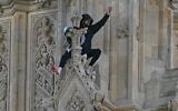Un manifestant tenant un drapeau palestinien fait un geste depuis le côté de la Tour Elizabeth, plus connue sous le nom de « Big Ben », au Palais de Westminster, qui abrite les Chambres du Parlement, dans le centre de Londres, le 8 mars 2025. (Ben Stansall/AFP)