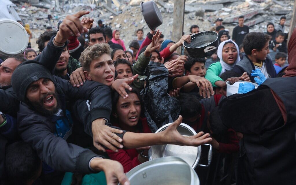 Des Palestiniens déplacés font la queue pour obtenir une portion de nourriture cuisinée dans une cuisine caritative à Beit Lahia, dans le nord de la bande de Gaza, avant le repas de rupture du jeûne pendant le mois du ramadan, le 9 mars 2025. (Crédit : Omar AL-QATTAA / AFP)