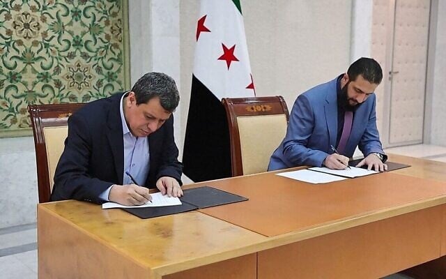 Le président par intérim syrien Ahmed al-Sharaa (à droite) et le commandant en chef des Forces démocratiques syriennes (FDS) Mazloum Abdi signant un accord visant à intégrer les institutions de l'administration kurde semi-autonome du nord-est dans le gouvernement national, dans la capitale syrienne Damas, le 10 mars 2025. (Crédit : SANA / AFP)