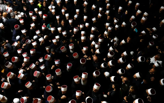Des personnes entourant des religieux druzes syriens à leur arrivée au tombeau de Nabi Shuaib, dans le nord d'Israël, le 14 mars 2025 (Crédit : Jalaa Marey/AFP)