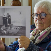 Gisèle Niango, née le 11 octobre 1943 dans une maternité "Lebensborn" en Belgique, l'une des nombreuses créées par le régime nazi allemand pour "l'expansion de la race aryenne", pose avec une photographie de son "Lebensborn" à Indersdorf, en Allemagne (Gisele est la 2e à droite sur la photo), lors d'une séance photo dans sa résidence pour personnes âgées à Nancy, dans le nord-est de la France, le 14 mars 2025. (Crédit : Jean-Christophe VERHAEGEN / AFP)