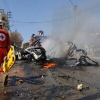 Un secouriste de la Croix-Rouge se dirigeant vers une voiture en feu après qu'elle a été touchée par une frappe israélienne, dans un village du sud du Liban le 15 mars 2025, au cours de laquelle une personne aurait été tuée. (Crédit : Rabih Daher/AFP)