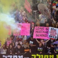 Des manifestants brandissant des pancartes et allument des fusées éclairantes lors d'une manifestation appelant à agir pour libérer les otages restants à Gaza, devant le siège du ministère de la Défense, à Tel Aviv, le 15 mars 2025. (Crédit : Jack Guez/AFP)