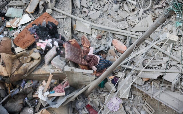 Une femme fouille les décombres de sa maison, détruite par une frappe israélienne, dans le camp de réfugiés de Nuseirat, dans le centre de la bande de Gaza, le 18 mars 2025. (Crédit : Eyad BABA / AFP) Une femme fouille les décombres de sa maison, détruite par une frappe israélienne, dans le camp de réfugiés de Nuseirat, dans le centre de la bande de Gaza, le 18 mars 2025. (Crédit : Eyad BABA / AFP)