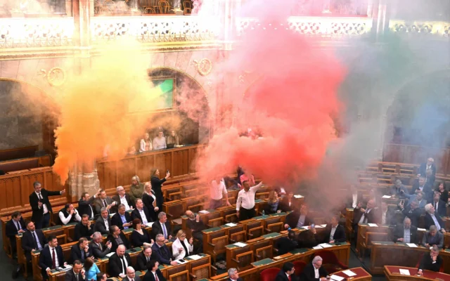 Des membres du parti centriste Mouvement Momentum brûlent des fusées en signe de protestation avant le vote d'un projet de loi visant à interdire la marche annuelle des fiertés, lors de la session de printemps du Parlement hongrois, le 18 mars 2025 . (Crédit : Attila KISBENEDEK / AFP) Des membres du parti centriste Mouvement Momentum brûlent des fusées en signe de protestation avant le vote d'un projet de loi visant à interdire la marche annuelle des fiertés, lors de la session de printemps du Parlement hongrois, le 18 mars 2025 . (Crédit : Attila KISBENEDEK / AFP)