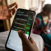 Une femme échange avec le chatbot de l'organisation IsraAID, basée en Israël, au camp de déplacés de Juba, au Soudan du Sud, le 12 février 2025. (AP Photo/Brian Inganga)