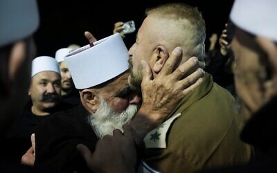 Un religieux druze (à gauche), qui a traversé la frontière entre la Syrie et Israël plus tôt dans la journée, accueilli par un soldat israélien dans l'enceinte du sanctuaire de Nabi Shuaib, dans le nord d'Israël, le 14 mars 2025. (Crédit : Leo Correa/AP)