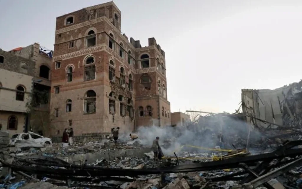 Des habitants inspectant le site qui aurait été frappé par des frappes aériennes américaines dans la nuit du 20 mars 2025 à Sanaa, au Yémen. (Crédit : AP Photo)