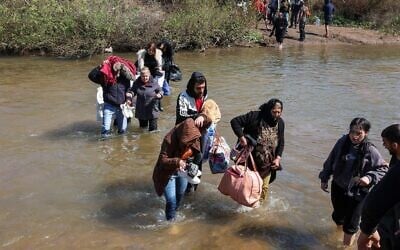Des Syriens alaouites, qui ont fui les violences dans l'ouest de la Syrie, avancent dans les eaux de la rivière Nahr El Kabir, suite au massacre de masse des membres de la minorité alaouite, à Akkar, au Liban, le 11 mars 2025. (Reuters/Mohamed Azakir)