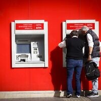 Des personnes retirent de l'argent d'un distributeur appartenant à la banque Hapoalim, à Tel Aviv, le 9 décembre 2024. (Miriam Alster/FLASH90)