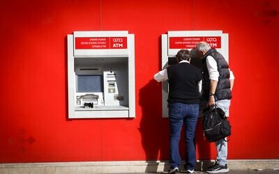 Des personnes retirent de l'argent d'un distributeur appartenant à la banque Hapoalim, à Tel Aviv, le 9 décembre 2024. (Miriam Alster/FLASH90)