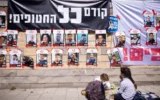 Des affiches d'Israéliens otages à Gaza devant le ministère de la Défense à Tel Aviv, sous une banderole indiquant : « Les otages avant tout! » le 9 mars 2025. (Crédit : Miriam Alster/FLASH90)