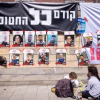 Des affiches d'Israéliens otages à Gaza devant le ministère de la Défense à Tel Aviv, sous une banderole indiquant : « Les otages avant tout! » le 9 mars 2025. (Crédit : Miriam Alster/FLASH90)