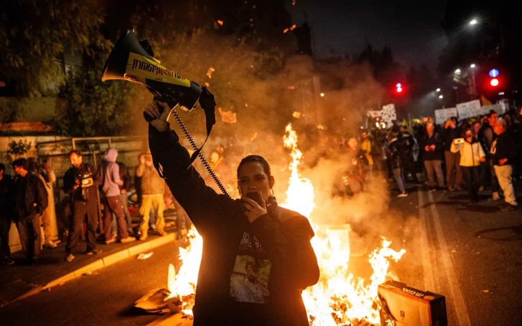 Des manifestants antigouvernementaux allument un feu sur la rue Azza à Jérusalem, le 19 mars 2025. (Crédit : Chaim Goldberg/Flash90)