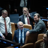 Le Premier ministre Benjamin Netanyahu et les législateurs de la coalition assistent à un vote sur le budget de l'État pour 2025 en séance plénière de la Knesset, le 19 mars 2025. (Crédit : Yonatan Sindel/Flash90)