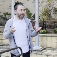 Le journaliste d'extrême gauche Israel Frey s'adresse à ses soutiens devant un commissariat de police à Tel Aviv, le 12 mars 2025. (Capture d'écran : X/Oren Ziv/used in accordance with Clause 27a of the Copyright Law)