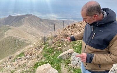 Des archéologues de l'Université Bar Ilan, en coopération avec l'officier d'état-major de l'archéologie, ont fouillé le site de Sartaba/Alexandrium dans la vallée du Jourdain en février 2025. Le directeur des fouilles, le Dr Dvir Raviv de Bar Ilan, montre un chapiteau de colonne sur le versant est de la colline. (Crédit : Rossella Tercatin/Times of Israel)