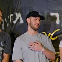 L'ex-otage Omer Shem Tov (au centre), Itay (à gauche) et Maya Regev alors qu'il s'adresse à une foule rassemblée pour le regarder décrocher une banderole appelant à sa libération, à Herzliya, le 13 mars 2025. (Crédit : Adar Eyal/Mouvement de protestation pour la démocratie)