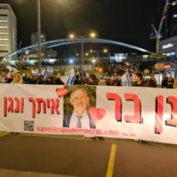 Des Israéliens manifestant à Tel Aviv portent une banderole en soutien à Ronen Bar, le chef du Shin Bet limogé par le Premier ministre Benjamin Netanyahu, le 22 mars 2025. (Crédit : Deborah Danan / JTA)