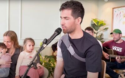 Sagui Dekel-Chen, sous le regard de son épouse Avital et de deux de leurs filles, chantant avec le Tamari Project, dans un clip diffusé le 28 février 2025. (Crédit : Capture d'écran/YouTube/The Tamari Project)