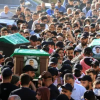 Des personnes en deuil transportent les cercueils du commandant du groupe terroriste Hamas Hassan Farhat (au centre), de son fils Hamza (à droite) et de sa fille Jenan (à gauche), tués lors d'une frappe israélienne qui a visé leur appartement dans la ville de Sidon, dans le sud du Liban, lors de leur cortège funèbre le 4 avril 2025. (Crédit : Mahmoud ZAYYAT / AFP)