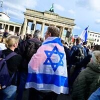 Un homme se couvre d'un drapeau israélien alors qu'il participe à un rassemblement de solidarité avec Israël à Berlin, en Allemagne, le 22 octobre 2023. (Crédit : John MACDOUGALL/AFP)