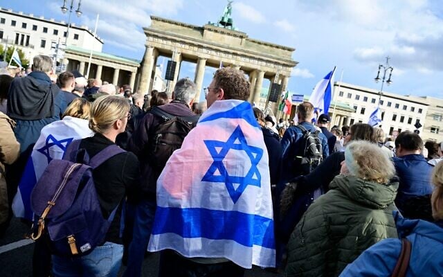 Un homme se couvre d'un drapeau israélien alors qu'il participe à un rassemblement de solidarité avec Israël à Berlin, en Allemagne, le 22 octobre 2023. (Crédit : John MACDOUGALL/AFP)