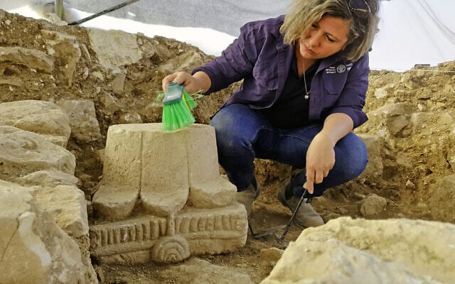 Anna Eirich, archéologue de l'Autorité israélienne des antiquités, nettoie un ancien chapiteau décoré de menorahs découvert à Jérusalem, qui sera exposé pour la première fois en mai 2025. (Crédit : Yoli Schwartz/Autorité israélienne des antiquités)