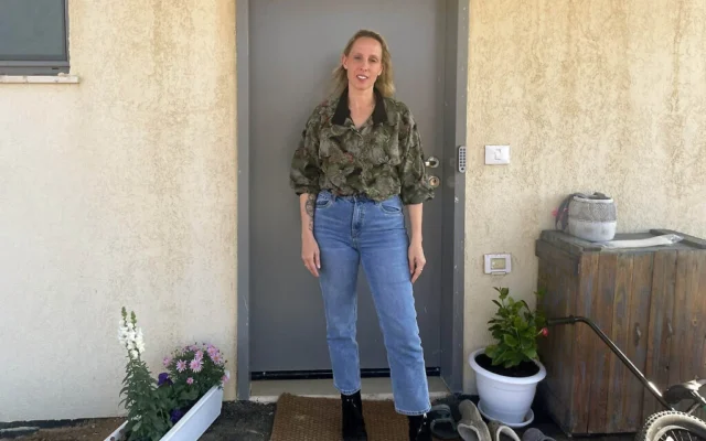 L'artiste Sofie Berzon Mackie devant son domicile temporaire au kibboutz Hatzerim, en mars 2025, après avoir été évacuée du kibboutz Beeri le 7 octobre 2023 et avoir vécu dans un hôtel près de la mer Morte pendant des mois avec son partenaire et ses trois enfants (Jessica Steinberg/Times of Israel)