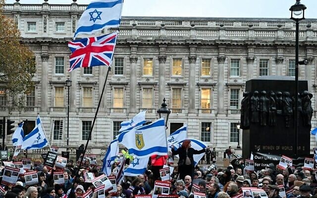 Des manifestants brandissant des drapeaux d'Israël et des photos de personnes prises en otage par le groupe terroriste palestinien du Hamas à Gaza, lors d'une manifestation pour protester contre l'antisémitisme et appeler à la libération des otages, devant Downing Street, le 19 novembre 2023. (Crédit : Justin Tallis/AFP)